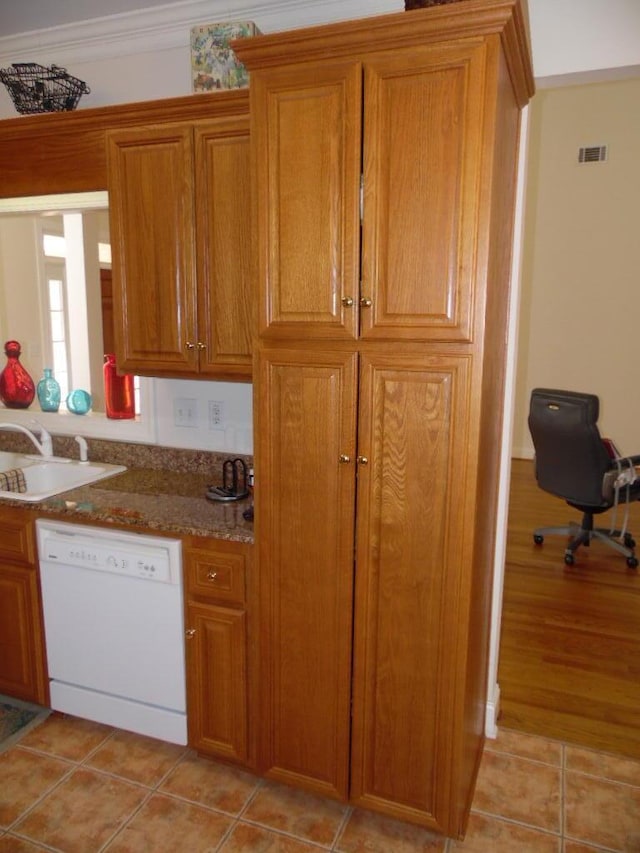 kitchen with sink, crown molding, light tile patterned floors, dishwasher, and stone counters