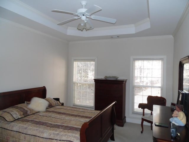 carpeted bedroom featuring a raised ceiling, crown molding, and ceiling fan