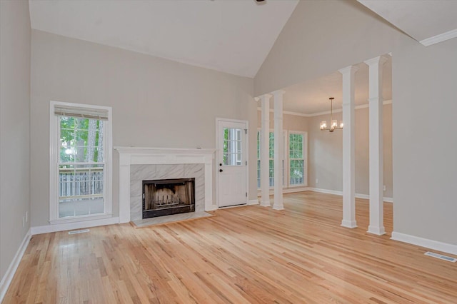 unfurnished living room featuring high vaulted ceiling, an inviting chandelier, ornate columns, light wood-type flooring, and a fireplace