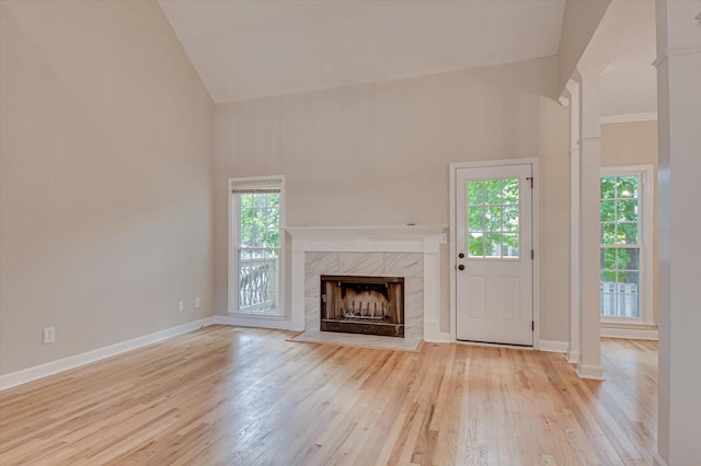 unfurnished living room featuring a fireplace, high vaulted ceiling, and light hardwood / wood-style flooring