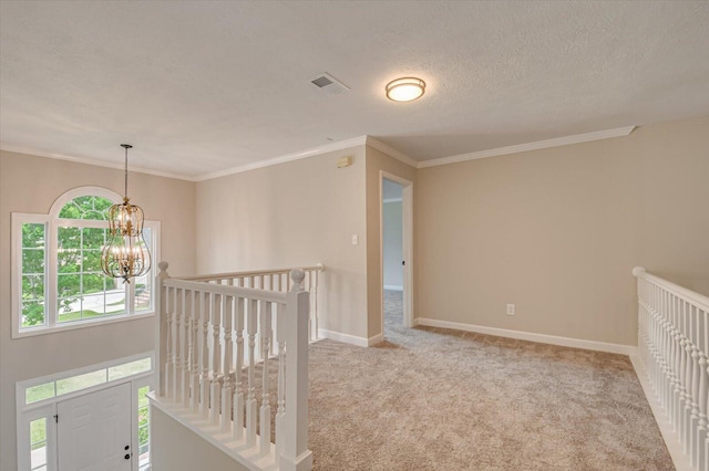 hallway with a textured ceiling, light colored carpet, an inviting chandelier, and crown molding