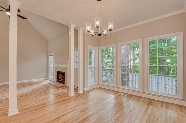 unfurnished living room featuring light hardwood / wood-style flooring, vaulted ceiling, a fireplace, ceiling fan with notable chandelier, and ornamental molding