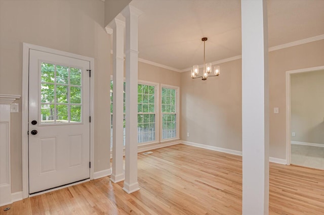 foyer with decorative columns, crown molding, light hardwood / wood-style floors, and a notable chandelier