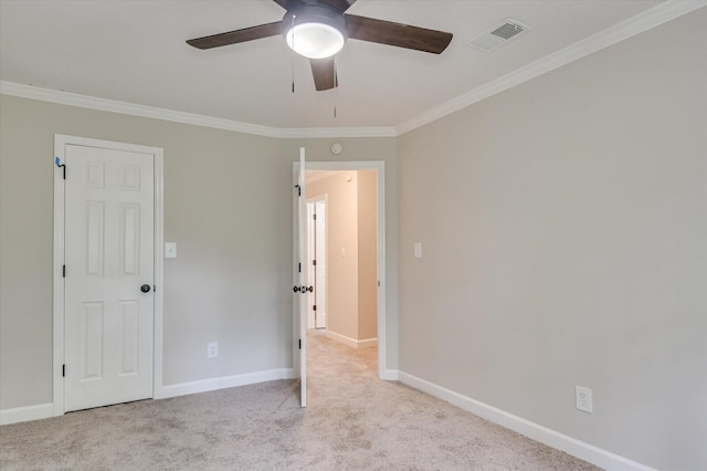 empty room featuring ceiling fan, crown molding, and light carpet