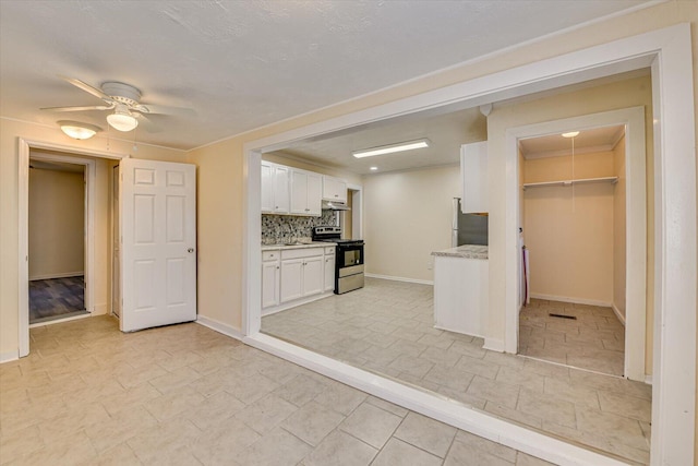 kitchen with white cabinets, stainless steel range with electric cooktop, under cabinet range hood, freestanding refrigerator, and ceiling fan