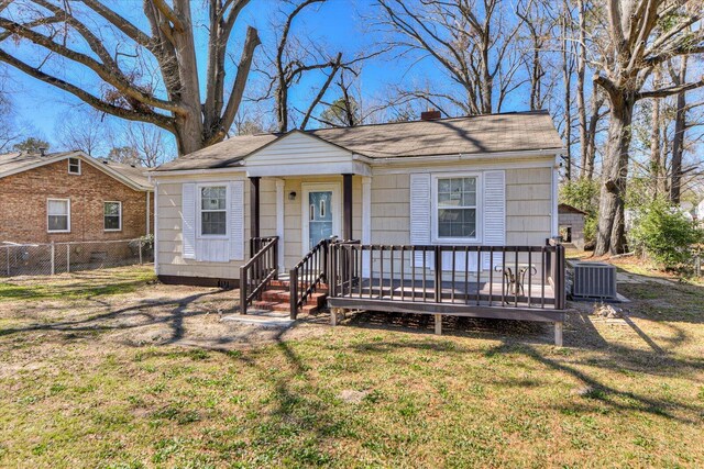 view of front of house featuring a wooden deck, a chimney, a front yard, and fence
