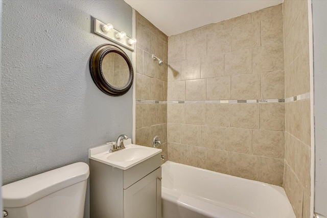 full bathroom featuring toilet, a textured wall, vanity, and tub / shower combination