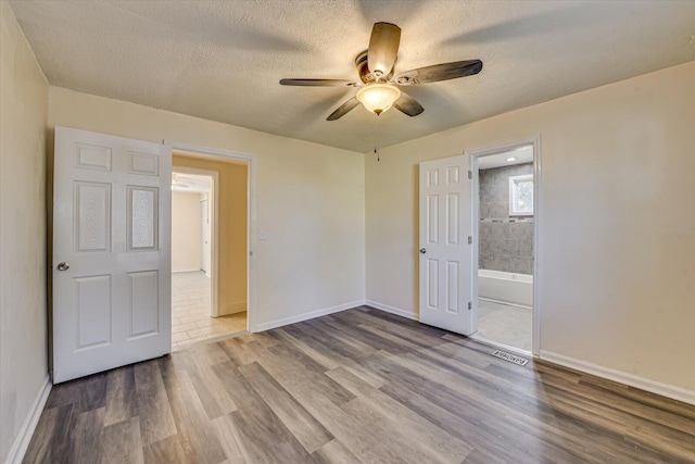unfurnished room featuring a textured ceiling, visible vents, baseboards, a ceiling fan, and wood finished floors