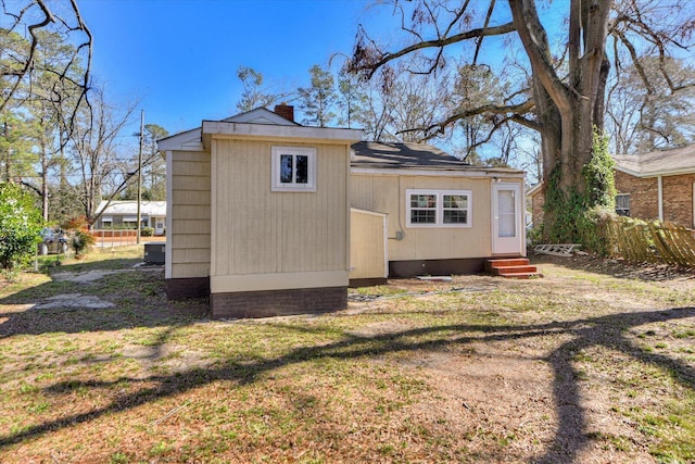rear view of property with a chimney, entry steps, and a yard