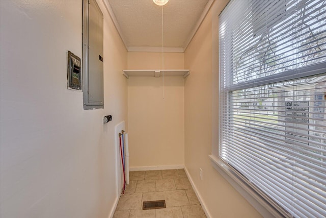 clothes washing area featuring light tile patterned flooring, a textured ceiling, laundry area, and plenty of natural light