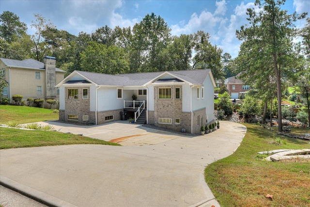 view of front of house with a front yard, concrete driveway, and brick siding