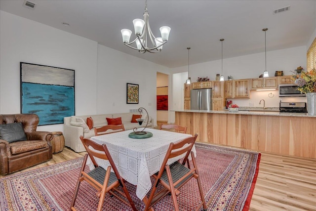 dining room featuring light wood finished floors and a chandelier