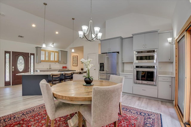 dining space with light wood-style floors, a chandelier, high vaulted ceiling, and recessed lighting