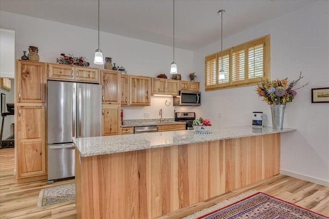 kitchen with appliances with stainless steel finishes, a peninsula, light wood-style flooring, light stone countertops, and hanging light fixtures