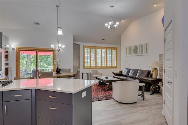kitchen with a chandelier, gray cabinets, light wood-type flooring, open floor plan, and decorative light fixtures