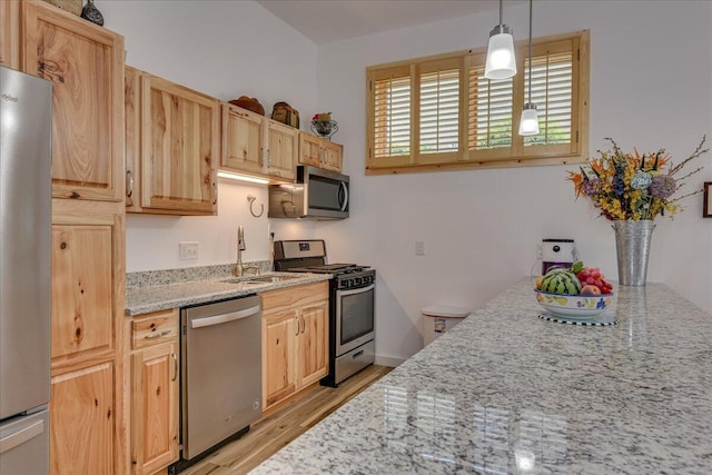 kitchen with stainless steel appliances, a sink, light brown cabinets, and light wood-style floors