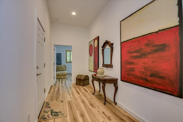hallway with light wood-type flooring, baseboards, and recessed lighting