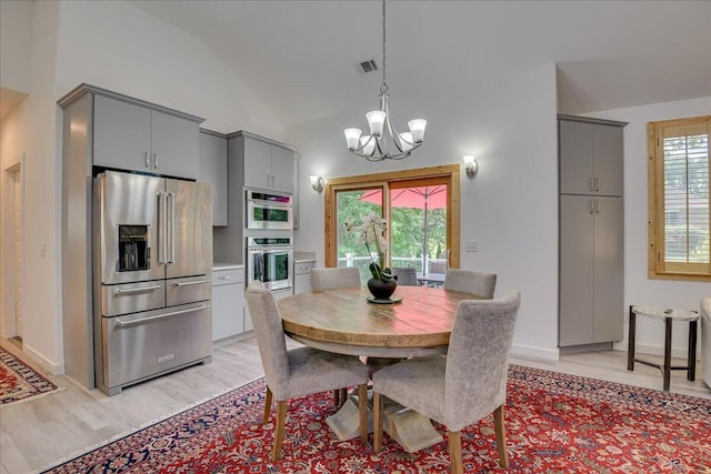 dining room with a chandelier, light wood finished floors, and high vaulted ceiling
