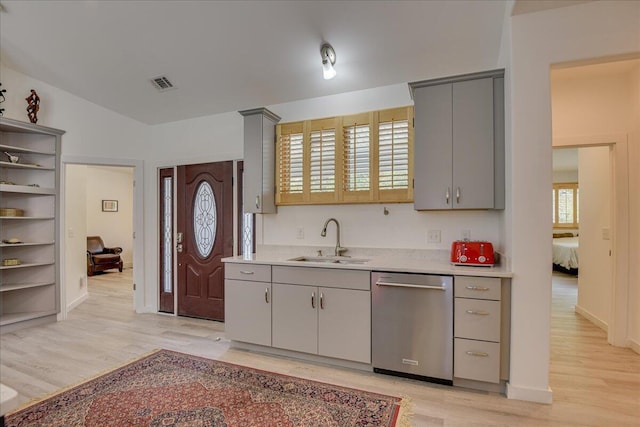 kitchen featuring stainless steel dishwasher, a sink, and gray cabinetry