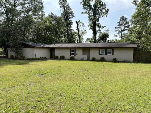 ranch-style house featuring stucco siding, fence, and a front lawn