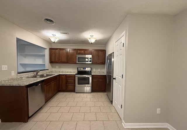kitchen with stainless steel appliances, light tile patterned flooring, light countertops, and a sink