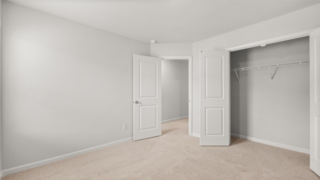 unfurnished bedroom with light carpet and a closet