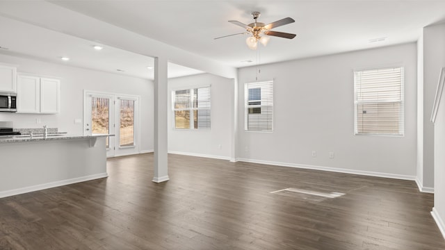 unfurnished living room with dark hardwood / wood-style floors, a wealth of natural light, and ceiling fan