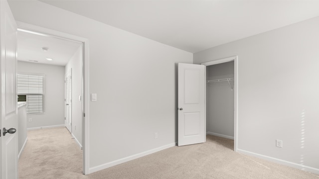 unfurnished bedroom with light carpet and a closet