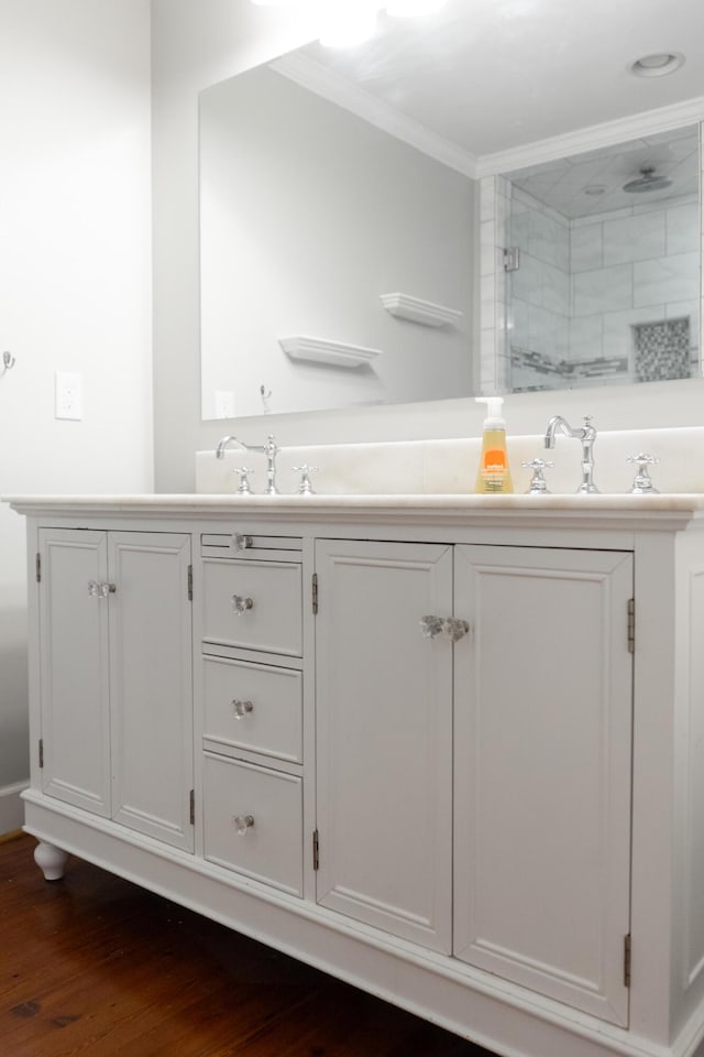 bathroom with hardwood / wood-style flooring, ornamental molding, vanity, and walk in shower