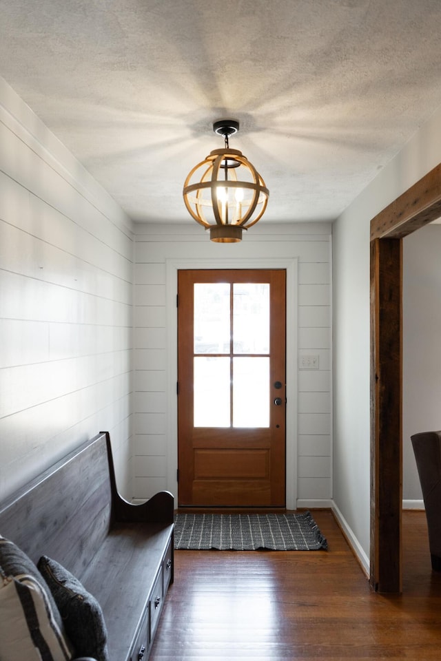 doorway to outside with dark hardwood / wood-style floors, a chandelier, and a textured ceiling