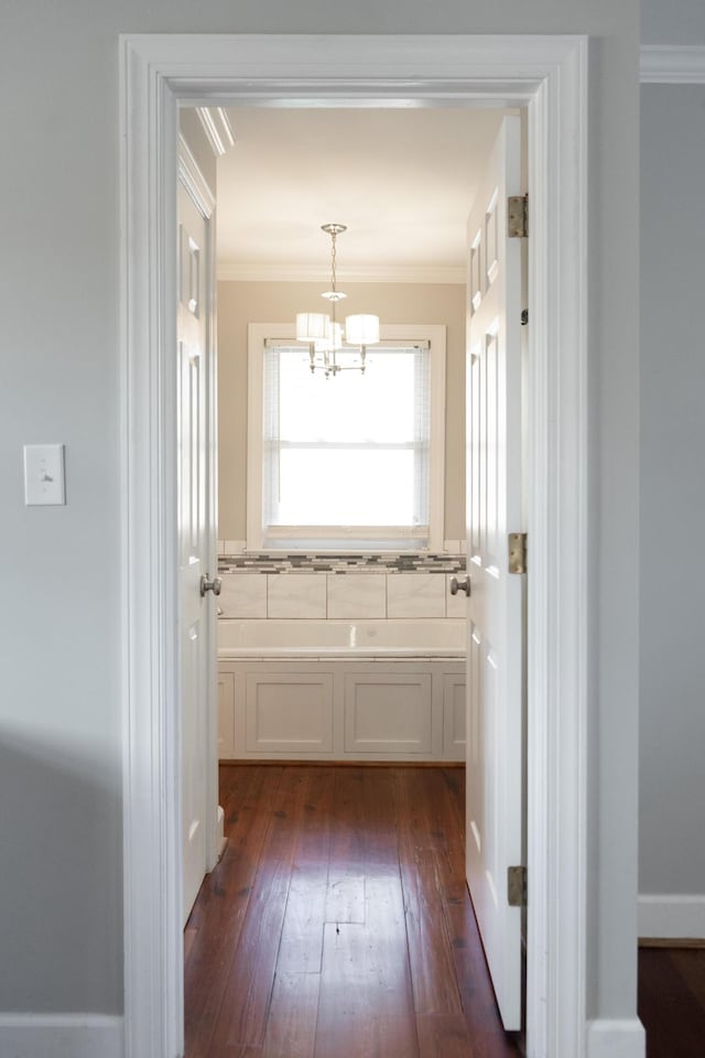 interior space with ornamental molding, wood-type flooring, backsplash, and an inviting chandelier