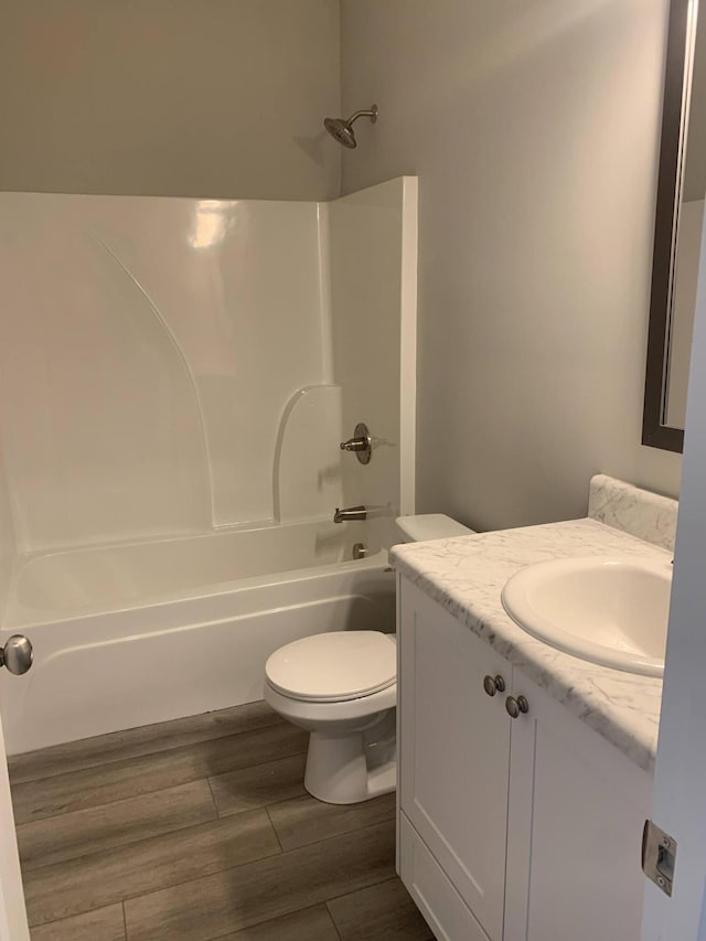 bathroom featuring washtub / shower combination, wood tiled floor, vanity, and toilet