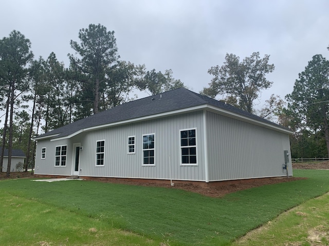 view of home's exterior with a shingled roof and a lawn