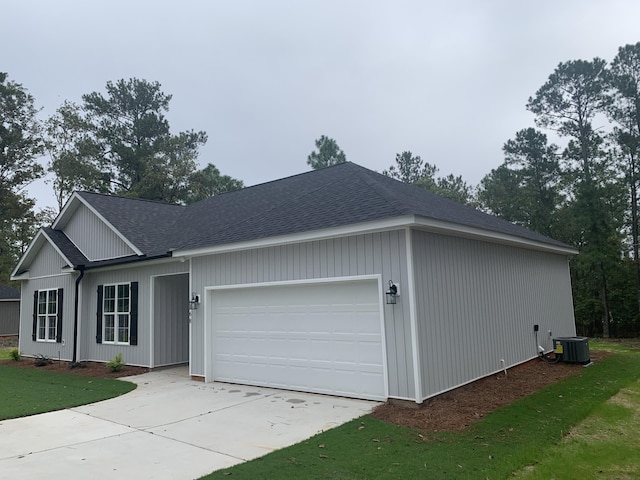 view of front of home featuring concrete driveway, roof with shingles, an attached garage, and cooling unit