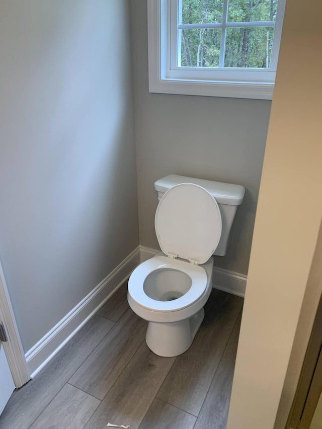 bathroom with baseboards, toilet, and wood finished floors