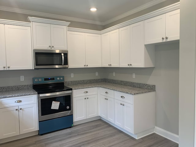 kitchen featuring stainless steel appliances, light wood-type flooring, white cabinetry, and crown molding