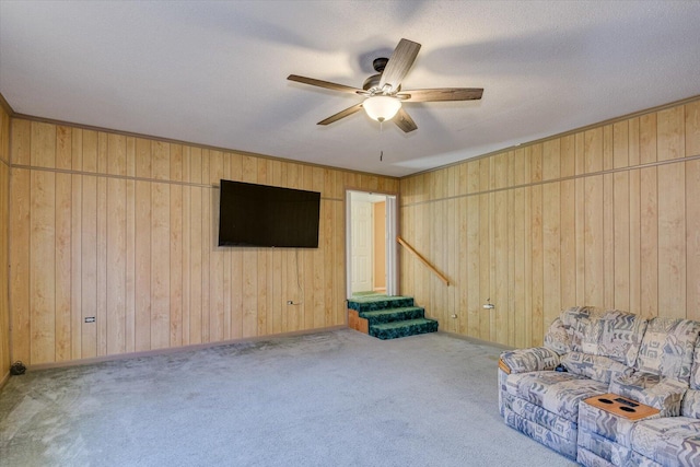 unfurnished room with light carpet, a textured ceiling, ceiling fan, and wood walls