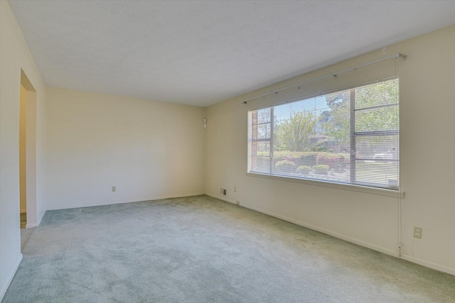 carpeted empty room featuring a textured ceiling