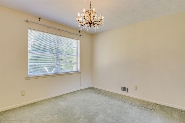 carpeted empty room with a chandelier