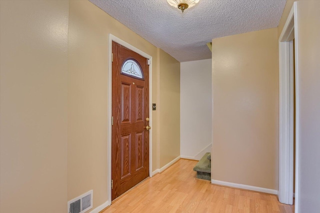 foyer entrance with a textured ceiling and light wood-type flooring