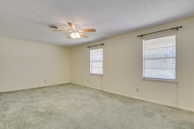 spare room featuring ceiling fan, light colored carpet, and a textured ceiling