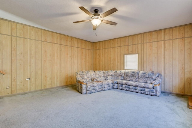 carpeted living room with ceiling fan and wooden walls