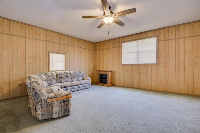 carpeted living room with wooden walls and ceiling fan