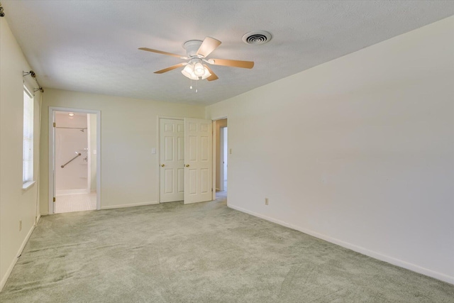 unfurnished room featuring ceiling fan, light colored carpet, and a textured ceiling