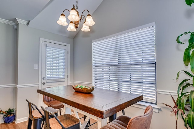 dining room featuring an inviting chandelier, crown molding, and vaulted ceiling