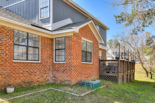 view of side of property featuring a wooden deck, brick siding, crawl space, a lawn, and board and batten siding