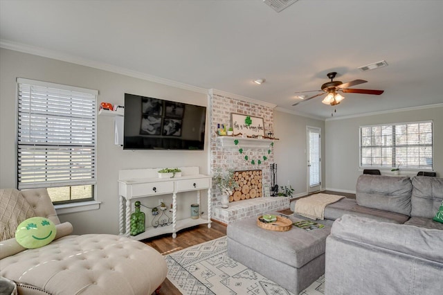 living area featuring visible vents, baseboards, ceiling fan, ornamental molding, and wood finished floors