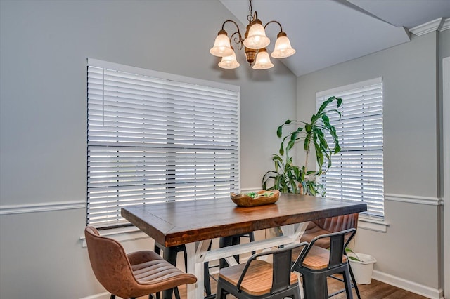 dining space featuring a chandelier, baseboards, lofted ceiling, and wood finished floors