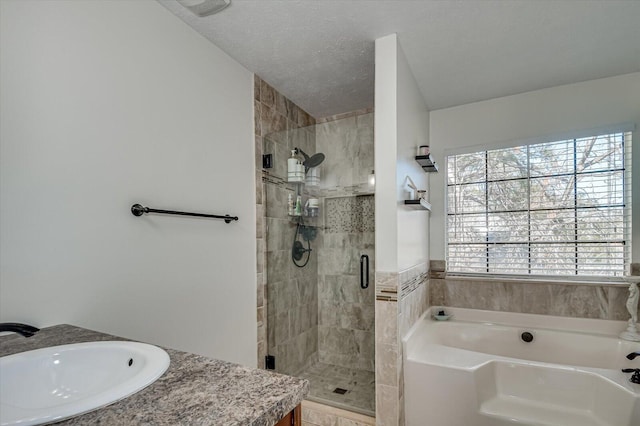 bathroom featuring vanity, a garden tub, a shower stall, and a textured ceiling