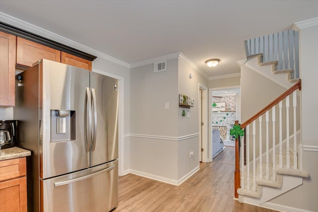 kitchen featuring visible vents, baseboards, light wood-style flooring, stainless steel refrigerator with ice dispenser, and crown molding